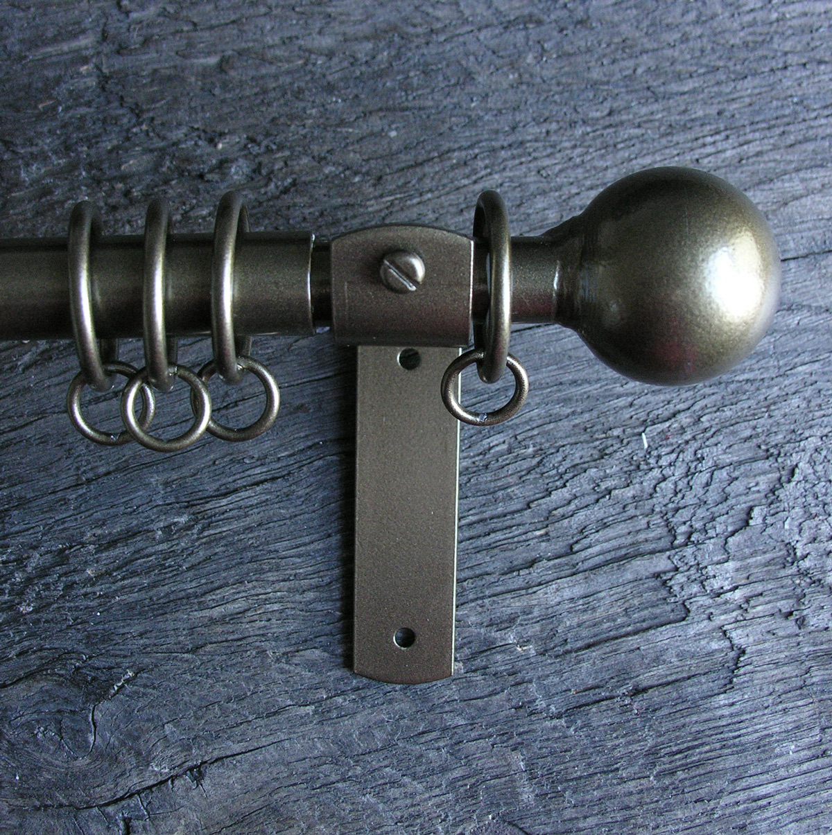 a slim bronze metal curtain pole with ball finials