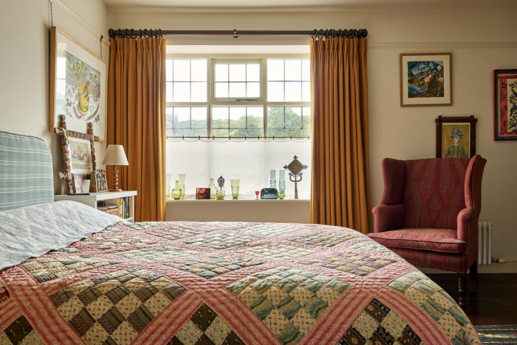 A classic bedroom with linen curtains and a patchwork quilt