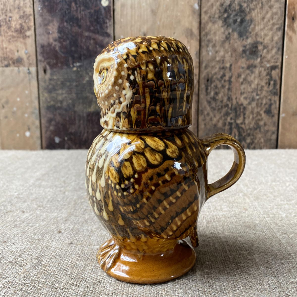 Carole Glover slipware glazed Owl Jug against a wooden background