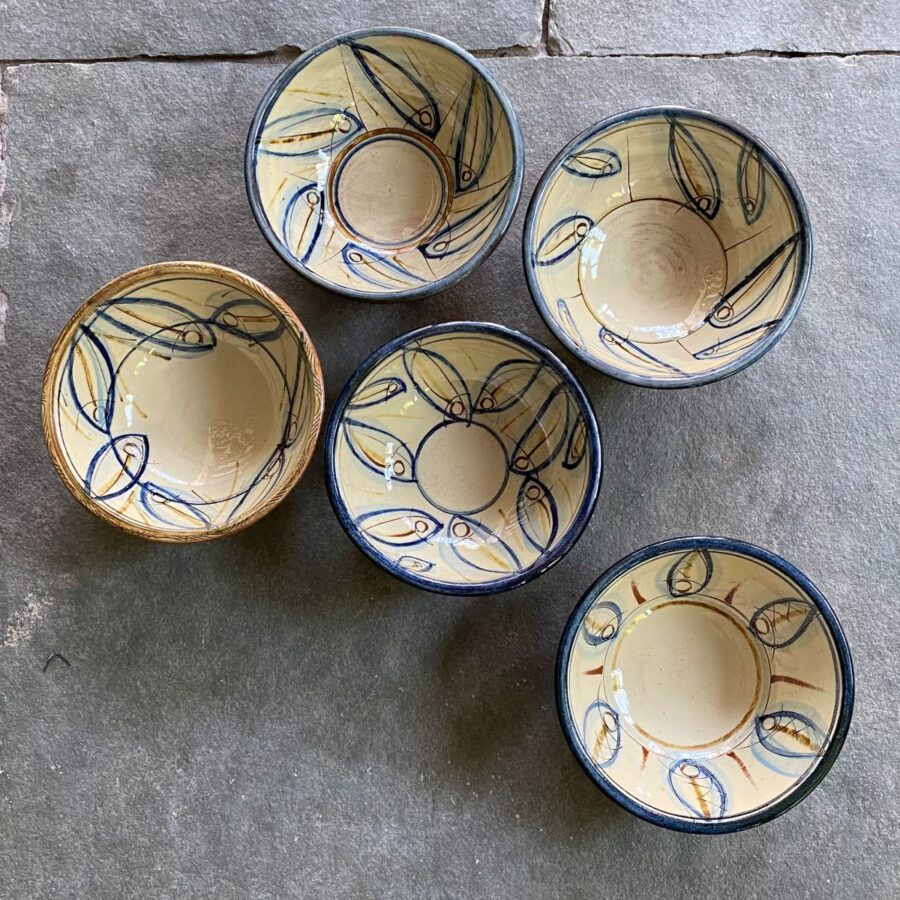 Group of slipware bowls with fish designs on a stone background