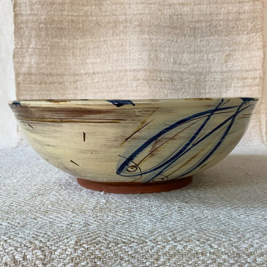 Side view of a cream glazed bowl by Jennifer Hall on a cream textile backcloth