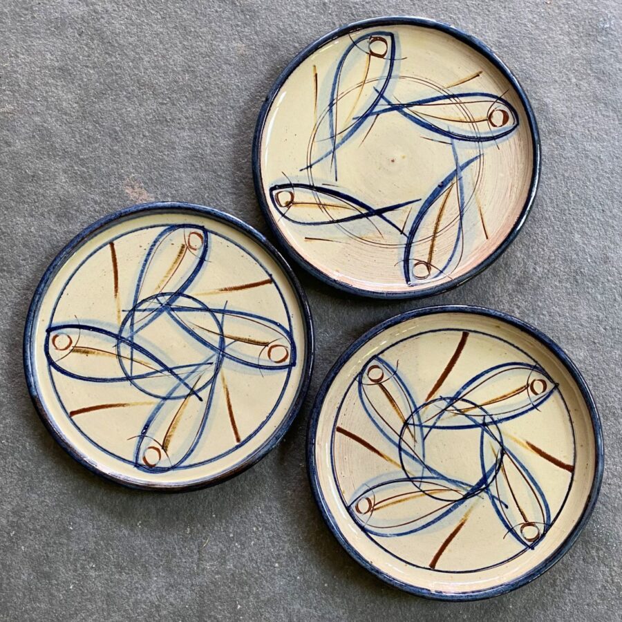Trio of side plates with slipware design on a grey stone background