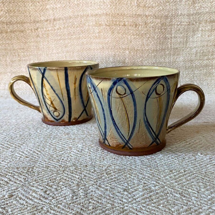 Jennifer Hall pair of slipware glazed tea mugs on a cream textile background