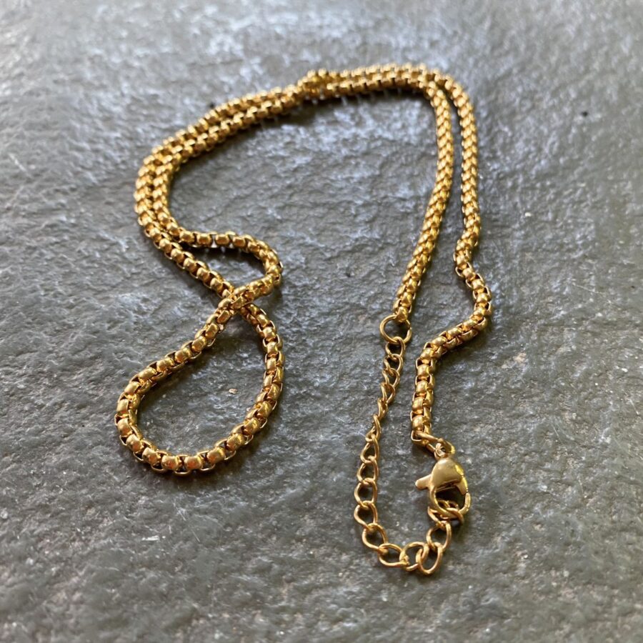 Gold box chain on a grey stone tile
