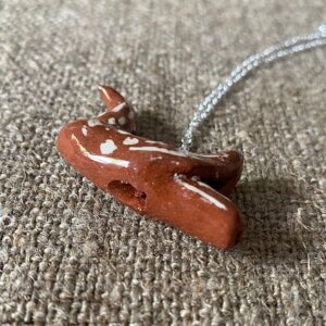 Emma Carlow pottery whistle necklace bird on a cloth background