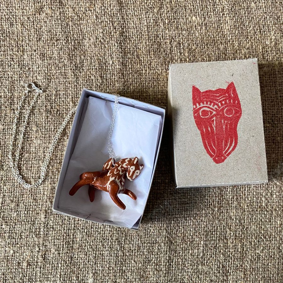 Emma Carlow pottery whistle necklace lion on a cloth background