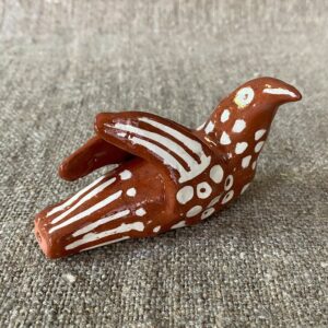 Emma Carlow pottery whistle in the shape of a bird on a cloth background
