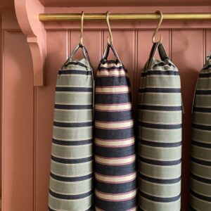 Trio of striped draught excluders hanging from hooks
