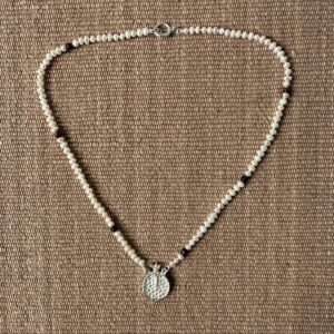 A seed pearl and red tigers eye necklace with a cast silver pomegranate pendant. Clare de la Torre.