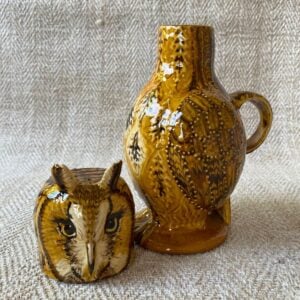 Ceramic slipware owl jug against a pale fabric background